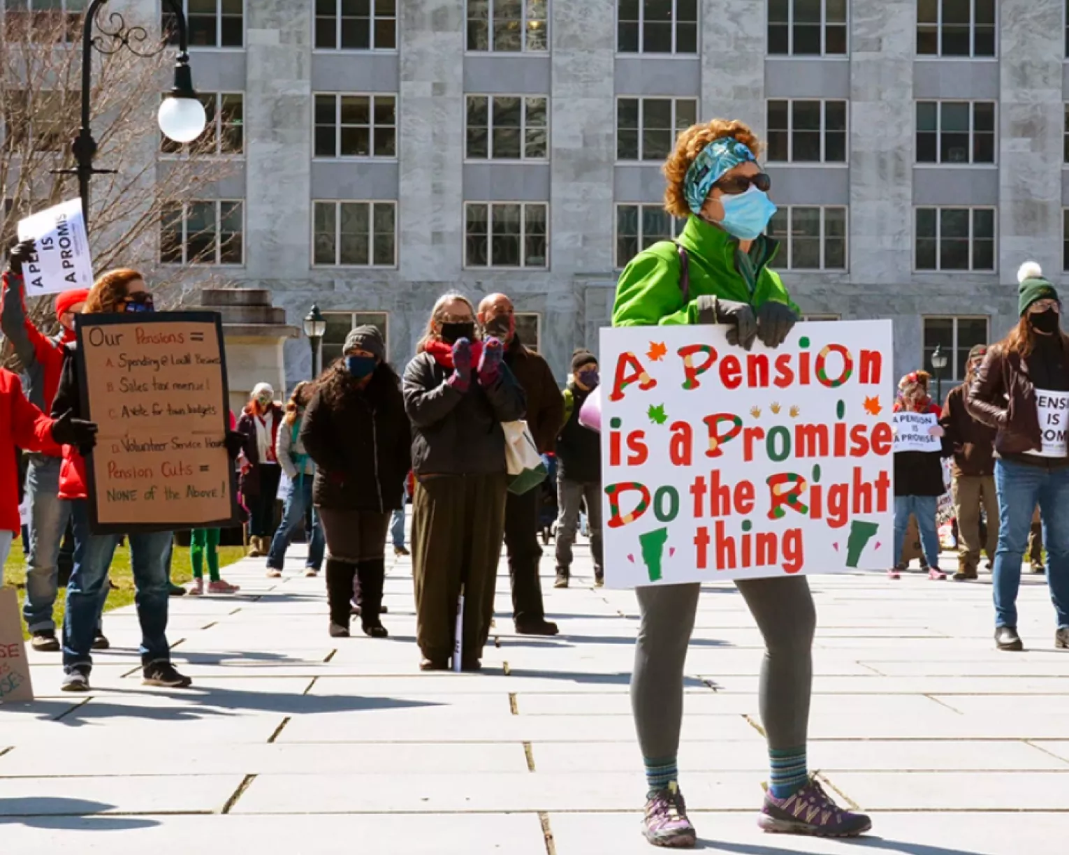 An educator stands with a sign that says, "A Pension is a Promise. Do the right thing!"