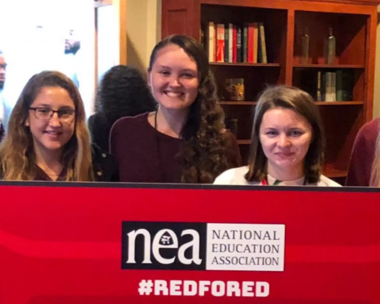 Aspiring Educators pose with a red for ed sign.