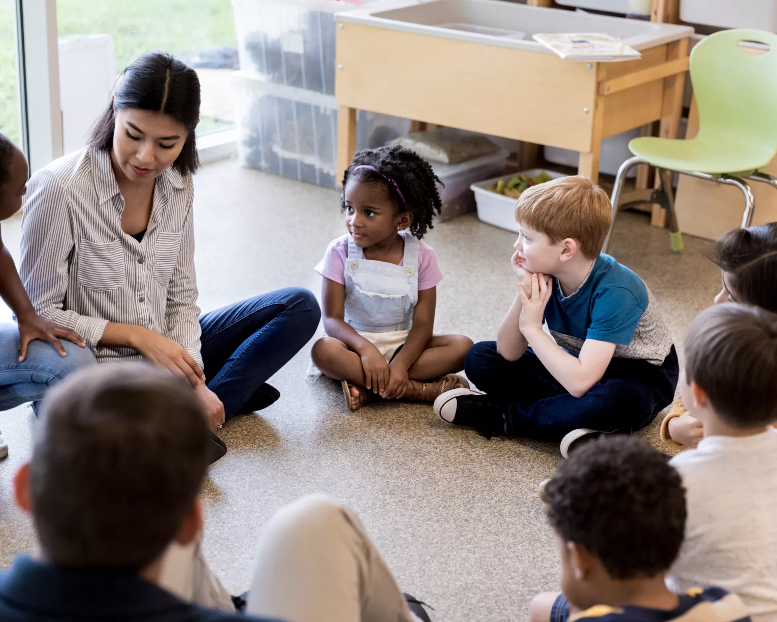 photo of educator sitting in a circle with a diverse group of students