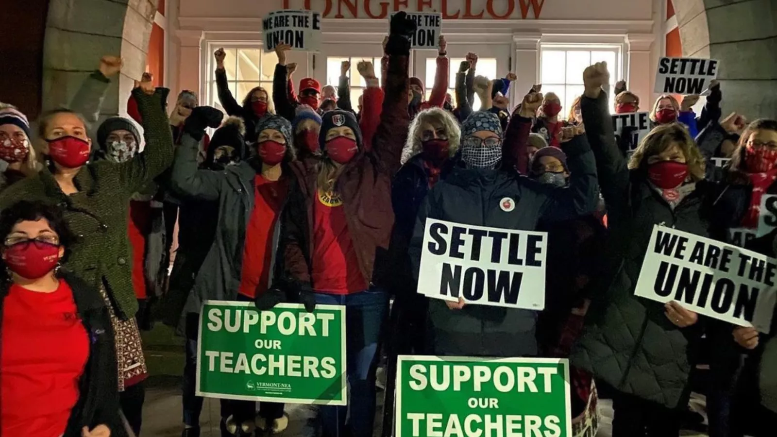Members stand in front of a building with the name "Longfellow" holding signs that say "Support Teachers" and "We are the Union!"