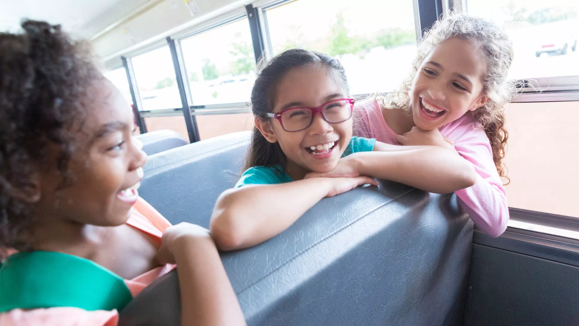 Elementary school students laugh together on a school bus.