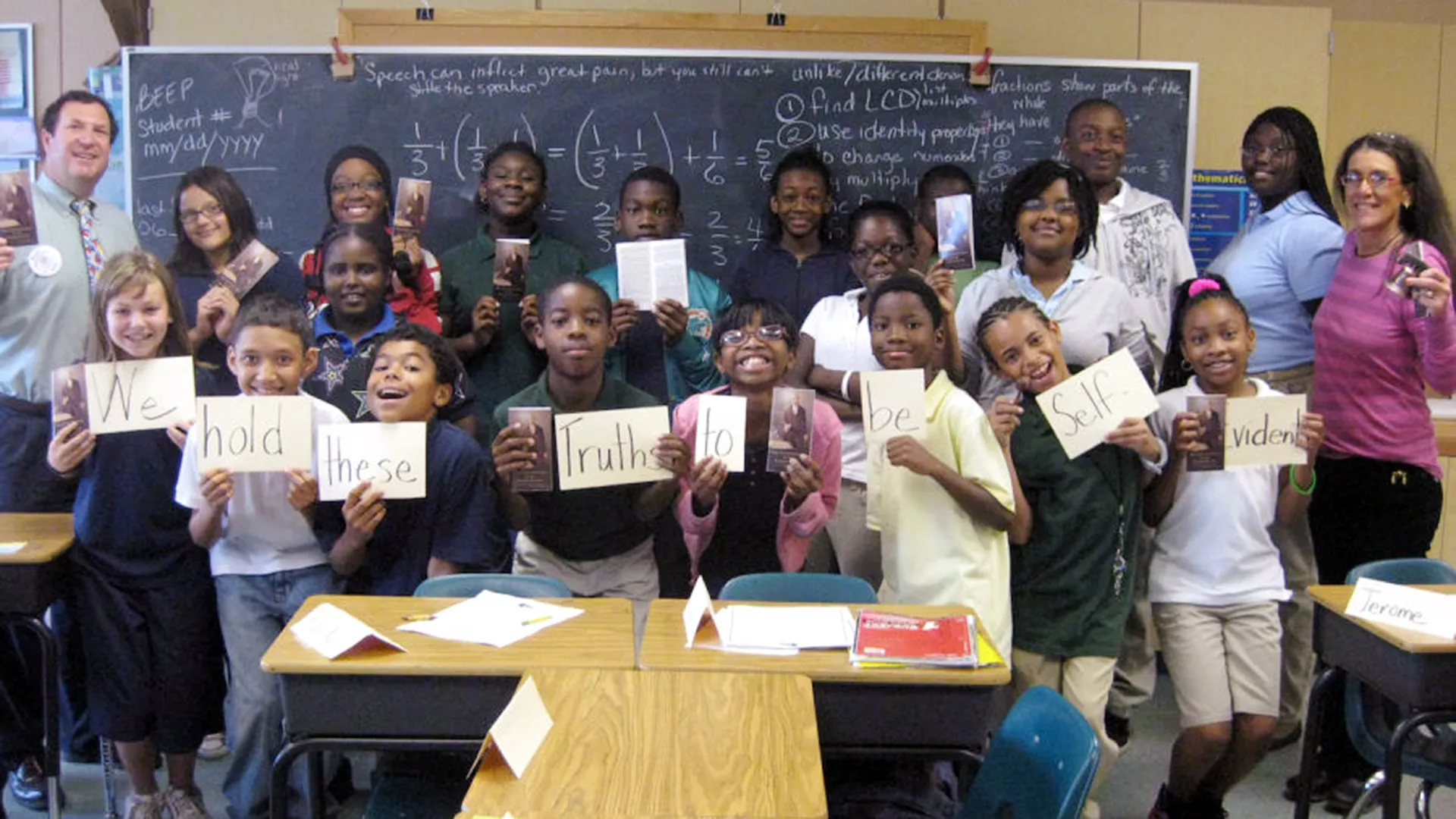 Fifth grade students pose in class holding up signs related to civics education