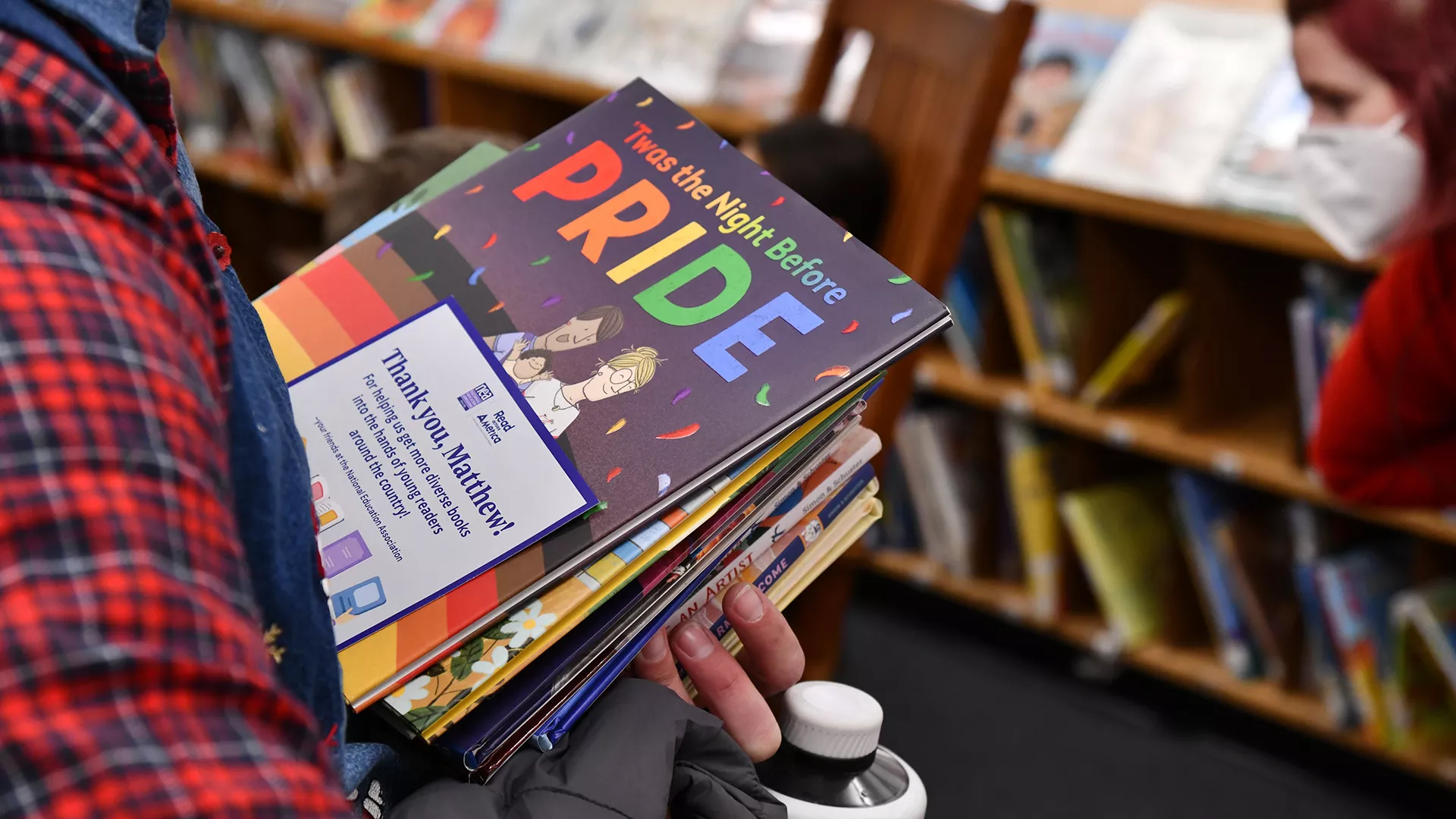 educator holds a stack of books with Twas the Night Before Pride on the top and visible
