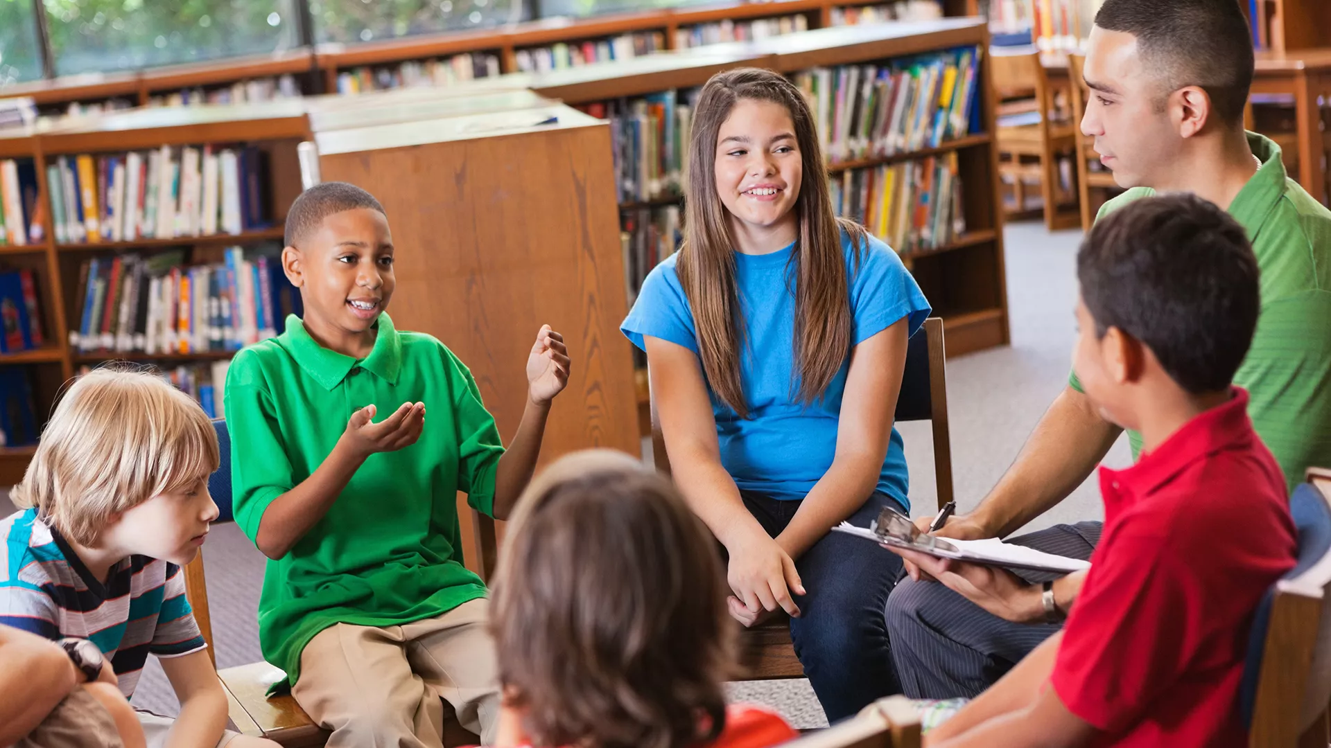 diverse students talking in a circle in school library