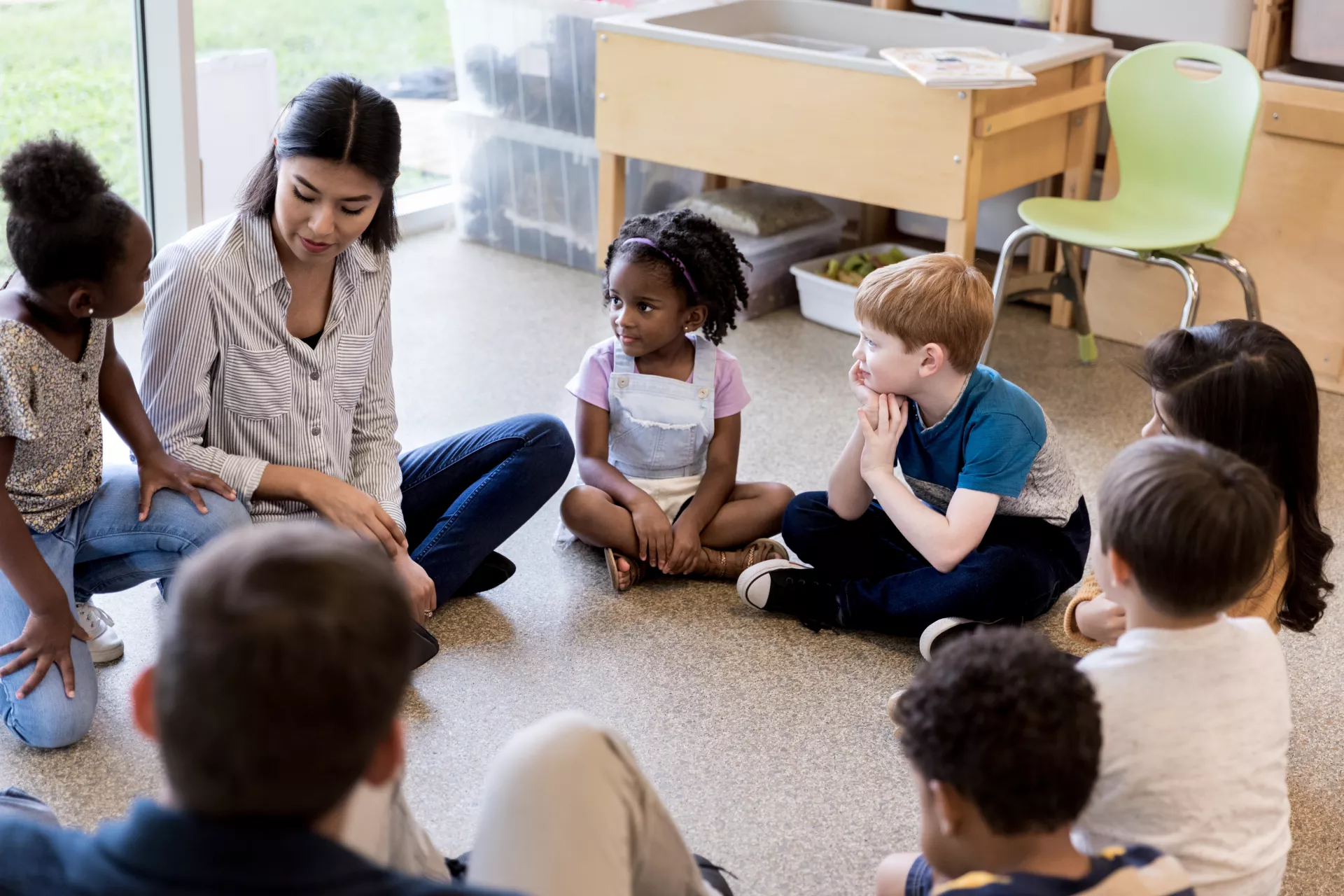 photo of educator sitting in a circle with a diverse group of students