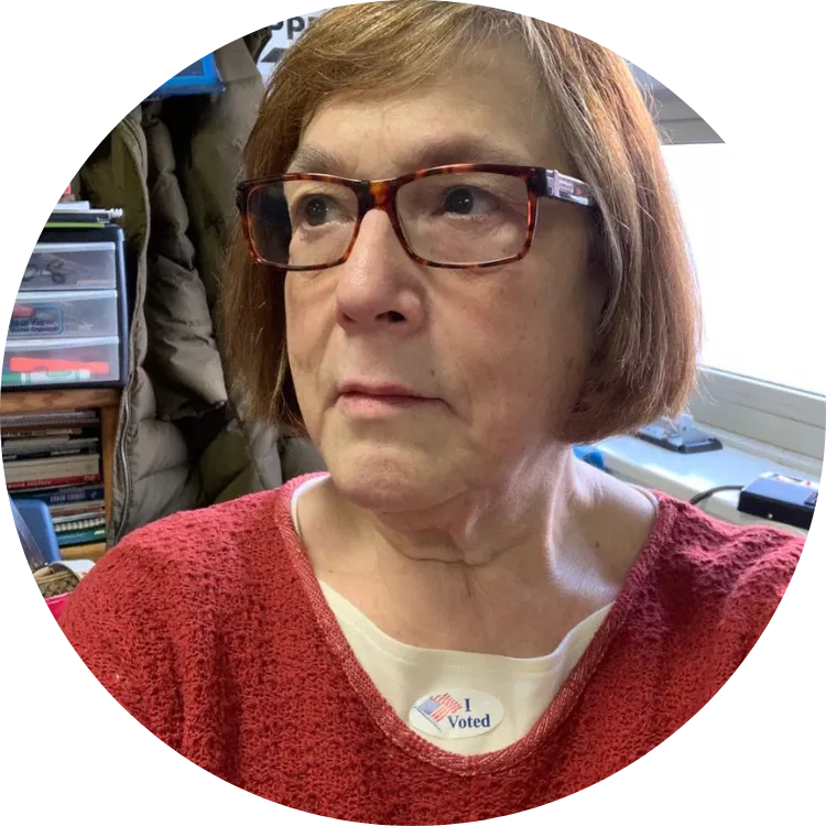 Fran Brock poses for a selfie in her classroom wearing an "I voted" sticker.
