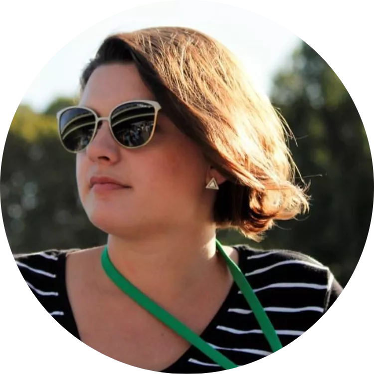 Emily Ide poses for a photo in sunglasses in a striped shirt with a green lanyard.