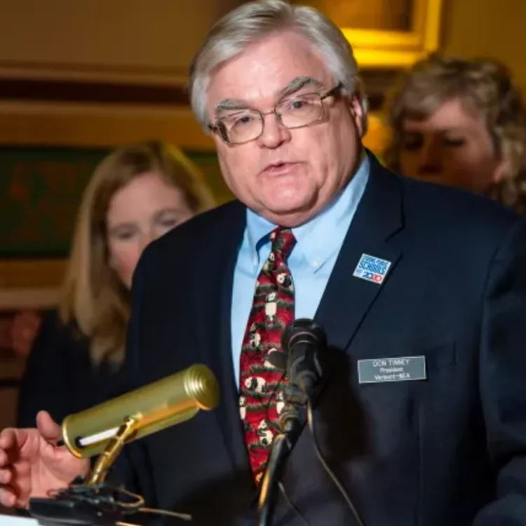 VT-NEA President Don Tinney addresses media at a microphone.